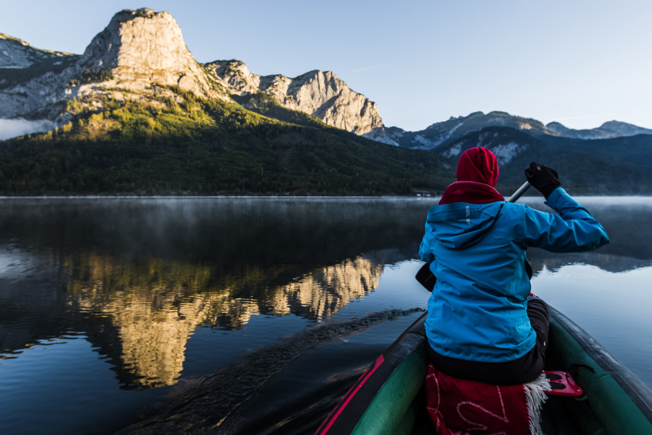 Person sitting on a boat and looking towards a mountain