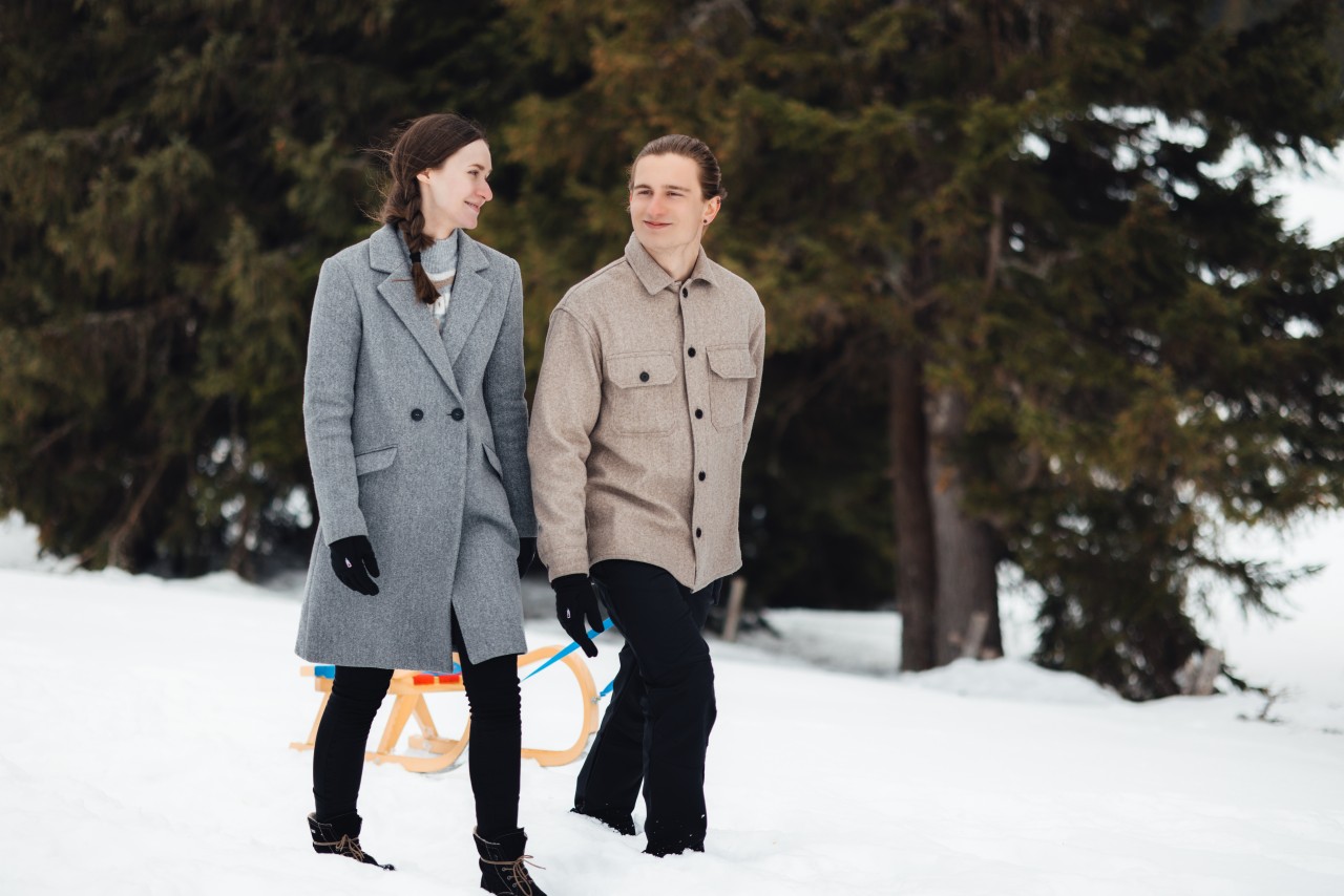 couple walking through forest in snow