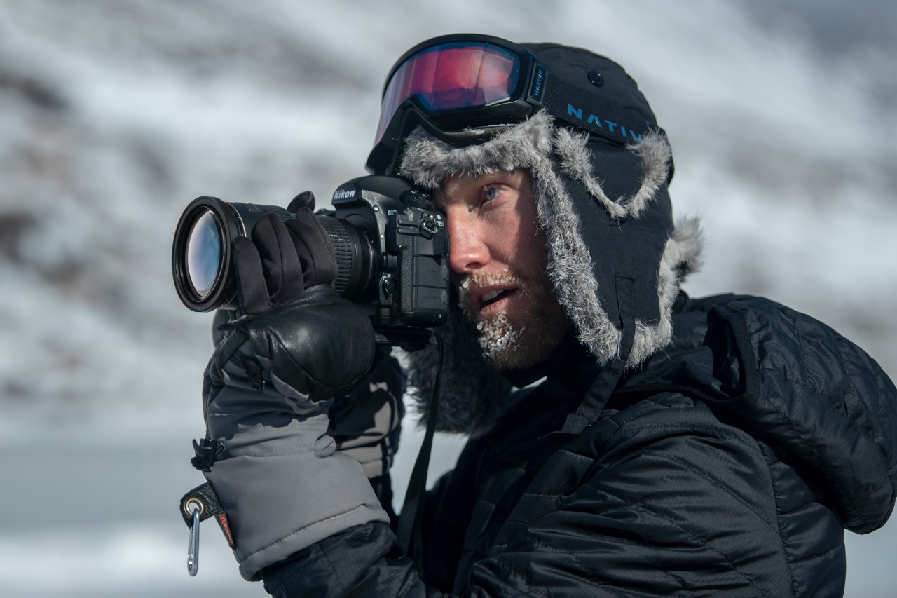 uomo che scatta foto in abiti invernali con guanti e muffole