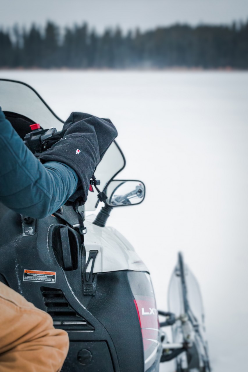 Close-up of a snowmobile with a person wearing overmitten