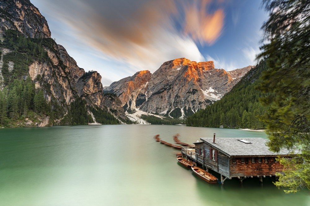 Eine Bootshütte mit Firscherbooten am grünen Pragser Wildsee und Bergen im Hintergrund