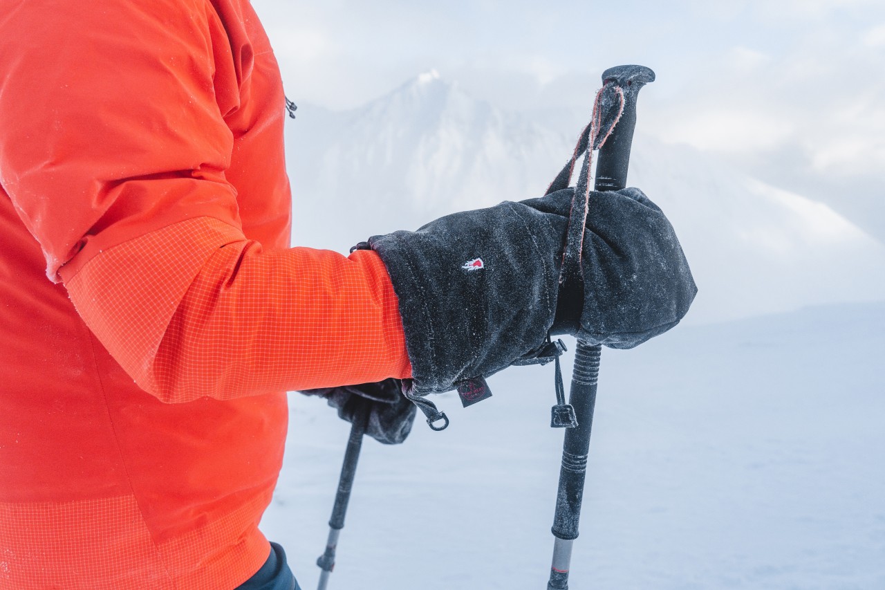 Man with pull-over mitten holding a ski pole