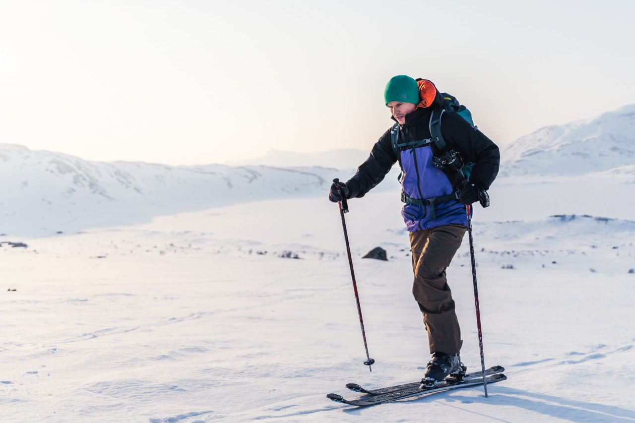 Mann mit Skiausrüstung macht eine Ski-Tour in den verschneiten Bergen
