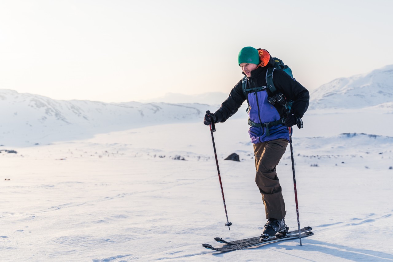 Man met ski-uitrusting gaat op skitocht in de besneeuwde bergen