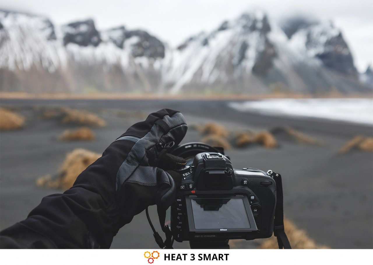 El fotógrafo de paisajes voltea la capa exterior para manejar la cámara con el guante de la capa debajo...