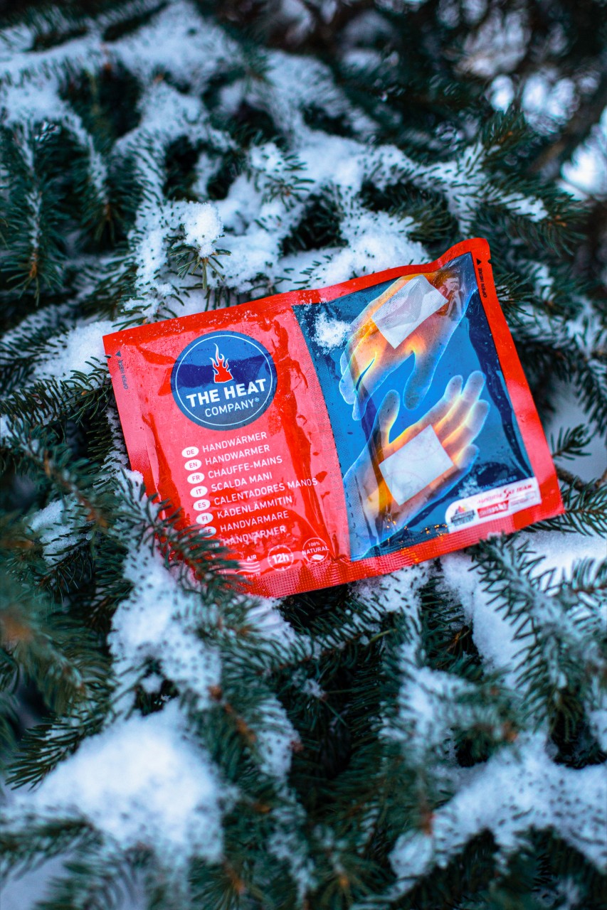 A hand warmer by THE HEAT COMPANY on a snow-covered branch 