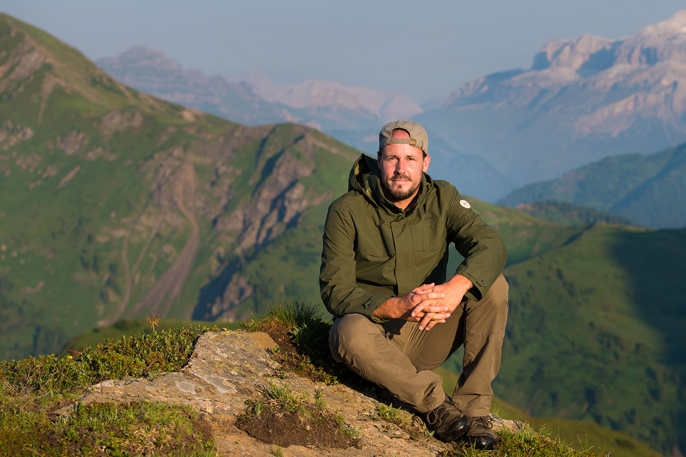 Portrait of travel photographer Arnold Schaffer sitting on a mountain with alpine landscape in warm evening light