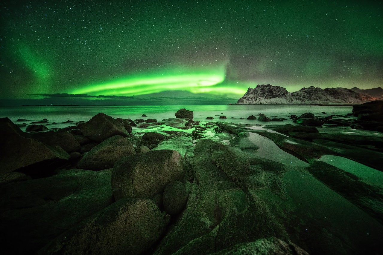 Polarlichtaufnahme auf den Lofoten in Norwegen, Uttakleiv, mit einem Weitwinkelobjektiv und Steinen im Vordergrund