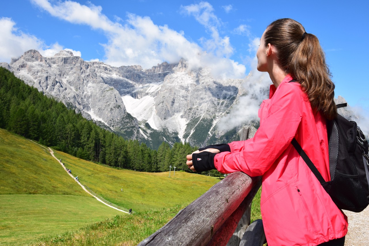 Woman admires meadows and mountains wearing fingerless gloves