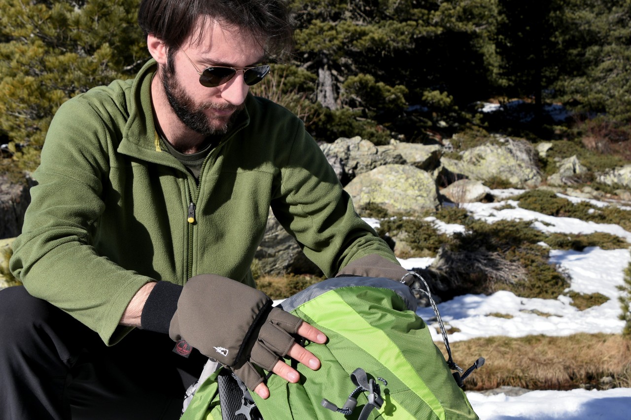 Man searching his backpack wearing fingerless mittens