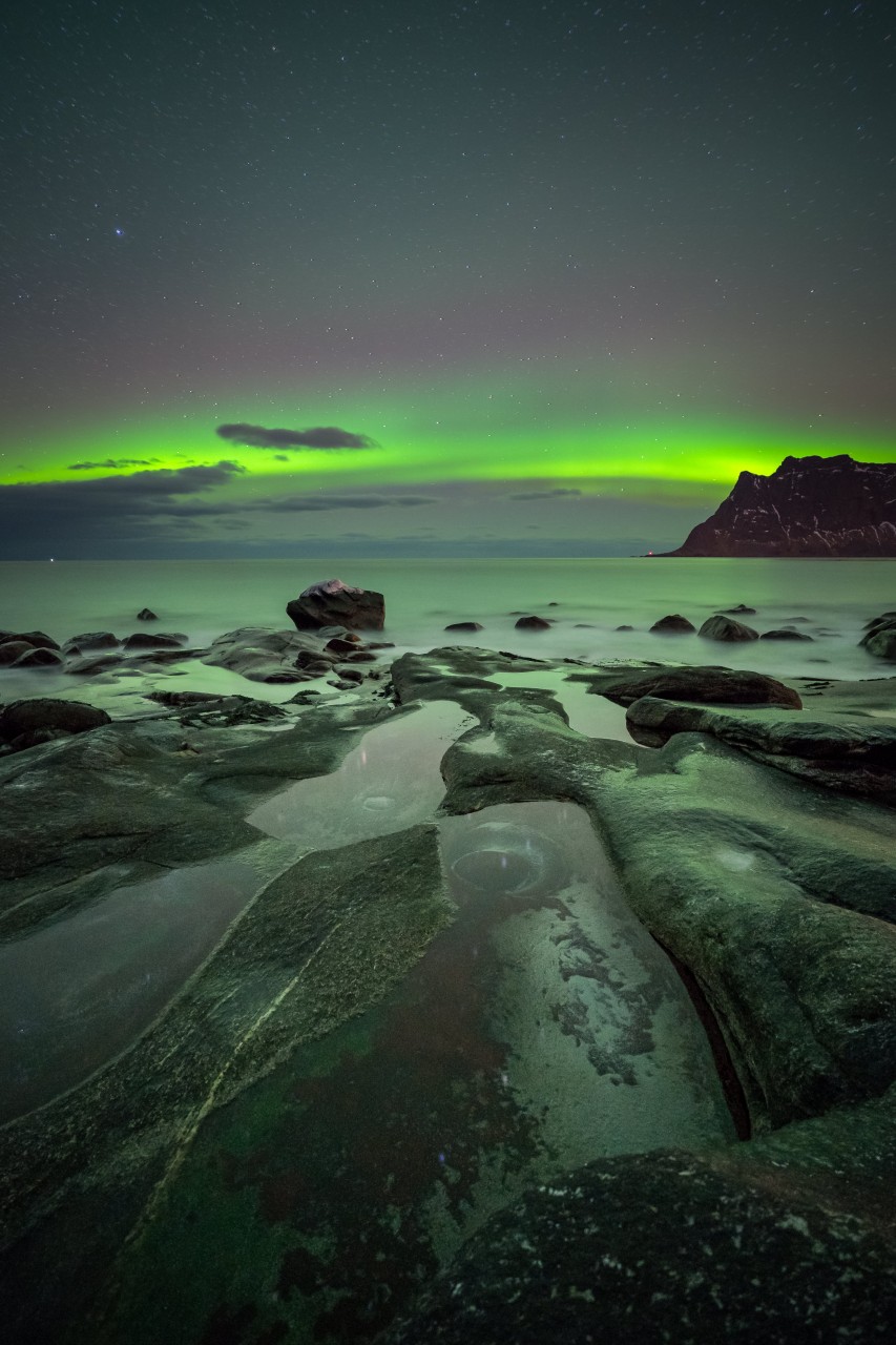 Northern lights with many rocks in the foreground