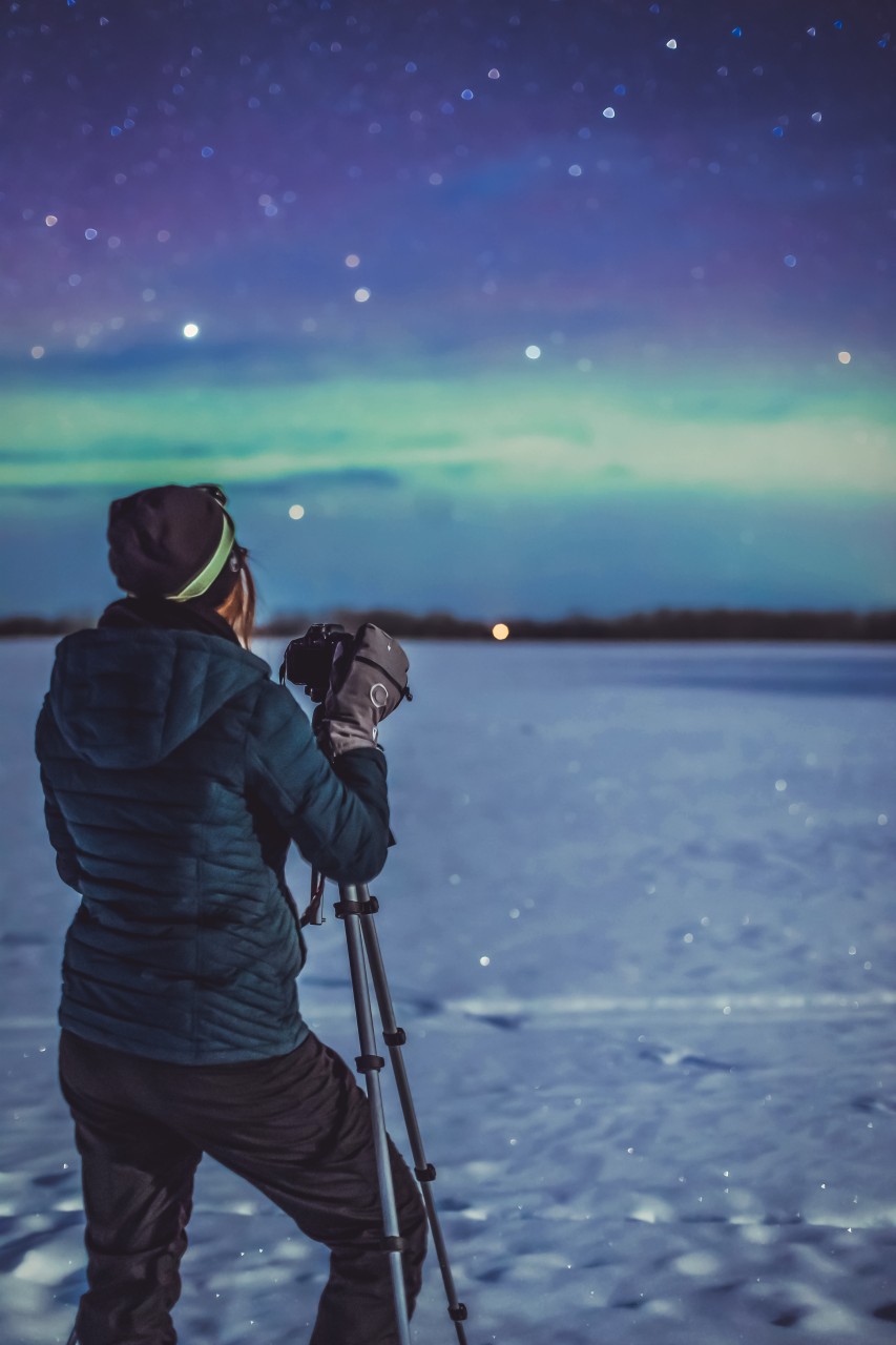 Photographe en hiver, avec des moufles, photographie la nuit étoilée