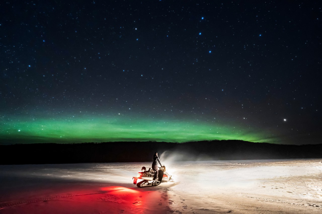 Mujer en moto de nieve bajo un cielo estrellado