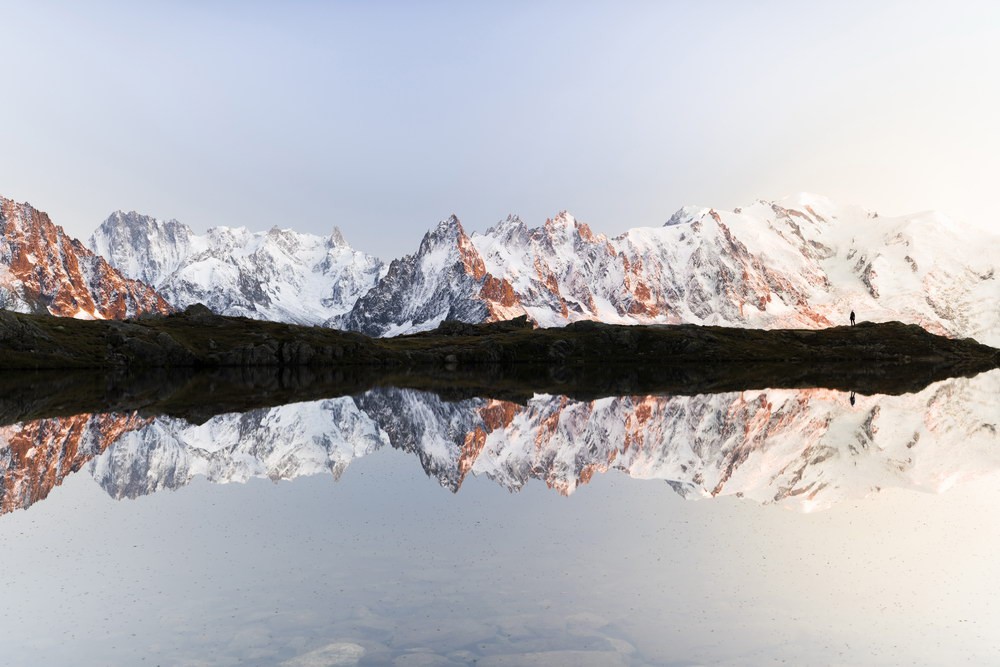 Reflection of a snow-covered chain of peaks in the mountain lake Lac de Cheserys 